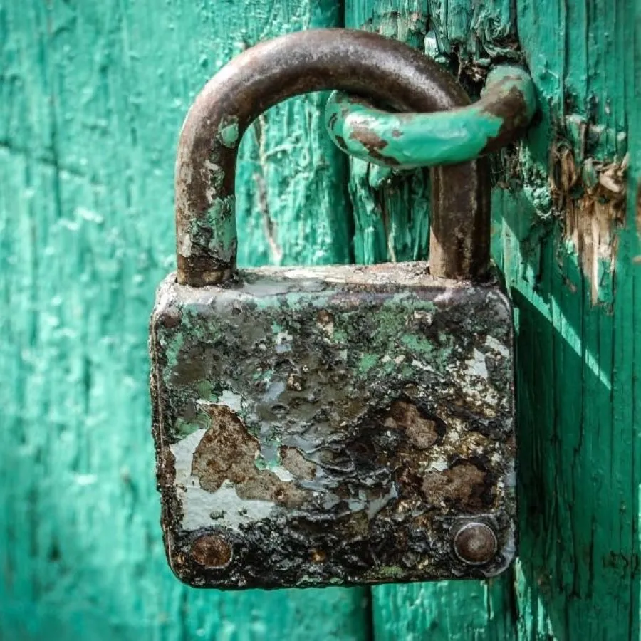A weathered iron padlock securing a painted wooden door.